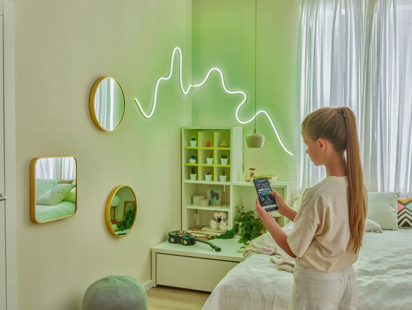  Dziewczynka sterująca nowoczesnym, neonowym oświetleniem ściennym za pomocą smartfona 